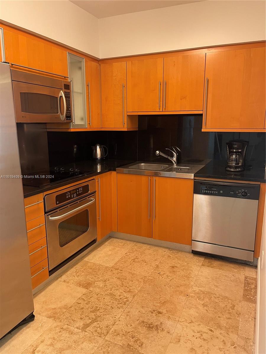 6365 Collins Avenue, Unit 2610 Miami Beach, FL 33141 - Photo 21 of 49 a kitchen with stainless steel appliances a stove a microwave and a sink
