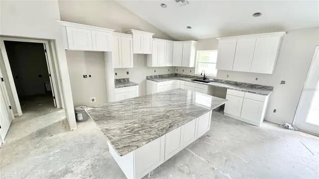 a large kitchen with granite countertop a stove refrigerator and sink