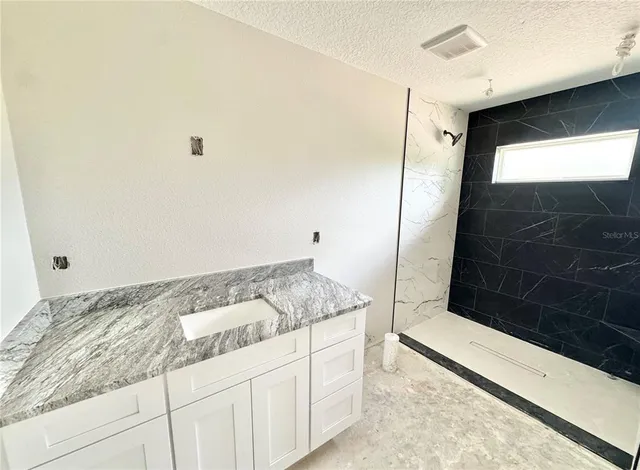 a bathroom with a granite countertop sink a toilet and shower