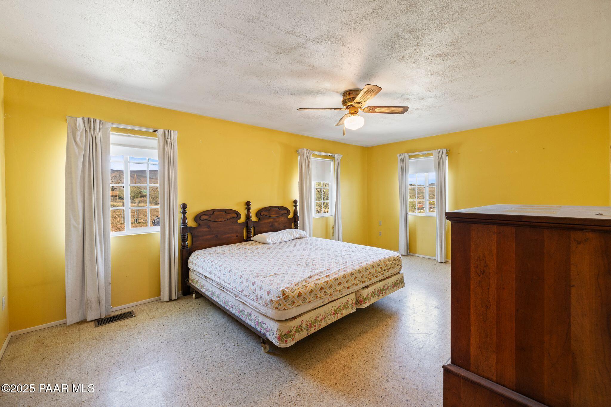 10231 Fir Street Mayer, AZ 86333 - Photo 18 of 50 a spacious bedroom with a bed and a chandelier