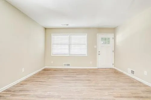 a view of an empty room with wooden floor and a window