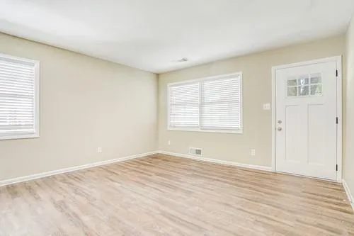 a view of an empty room with wooden floor and a window