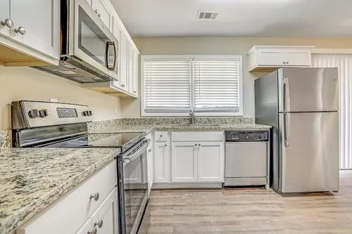 a kitchen with stainless steel appliances granite countertop a sink and a refrigerator