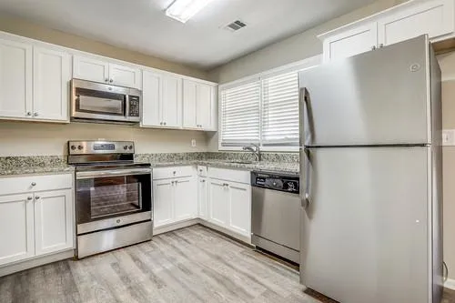 a kitchen with a refrigerator stove and white cabinets