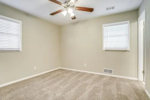 an empty room with a window and a fan
