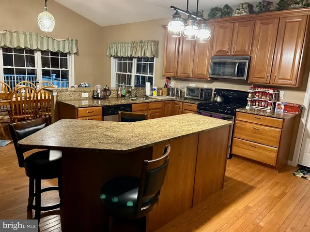 a kitchen with stainless steel appliances granite countertop a stove a sink dishwasher a dining table and chairs with wooden floor