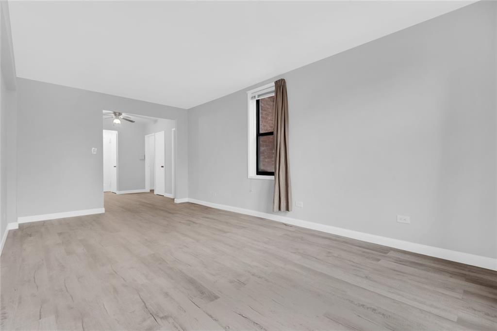 7259 Shore Road, Unit 2H Brooklyn, NY 11209 - Photo 4 of 9 a view of an empty room with wooden floor and a window