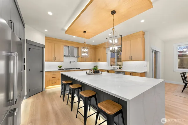 a kitchen with stainless steel appliances granite countertop a sink a stove a refrigerator and island with wooden floor