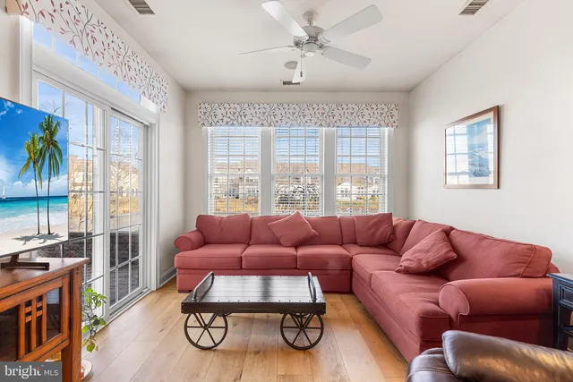 a living room with furniture ceiling fan and a large window