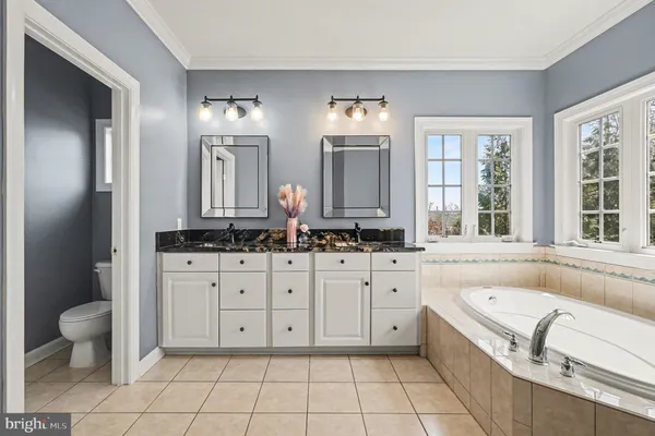 a spacious bathroom with a granite countertop sink toilet mirror and a bathtub