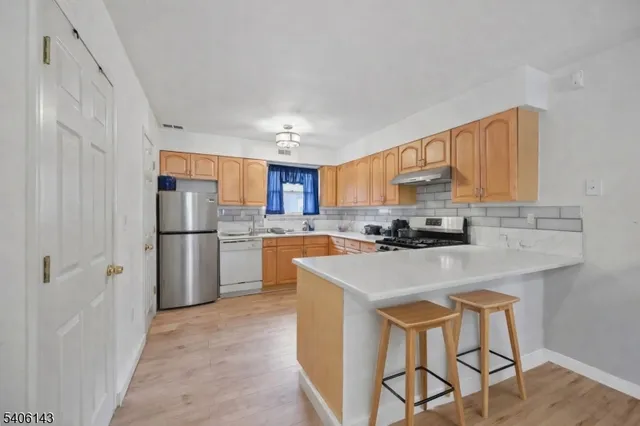 a kitchen with a refrigerator a sink dishwasher and a stove with wooden floor
