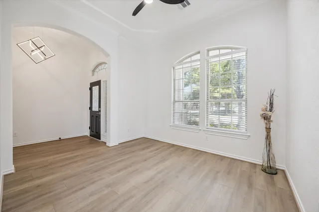 a view of an empty room with a window and wooden floor