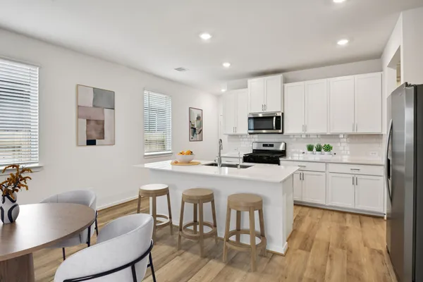 a kitchen with a dining table chairs microwave and refrigerator
