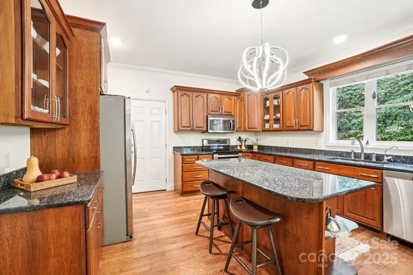 a kitchen with stainless steel appliances granite countertop a sink a stove and a wooden floors