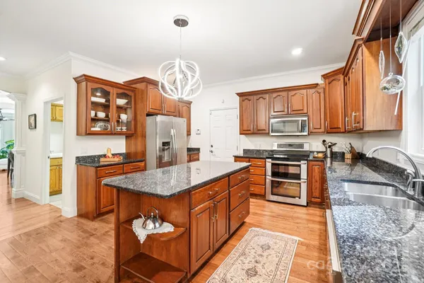 a kitchen with stainless steel appliances granite countertop a stove top oven a sink a counter space and cabinets