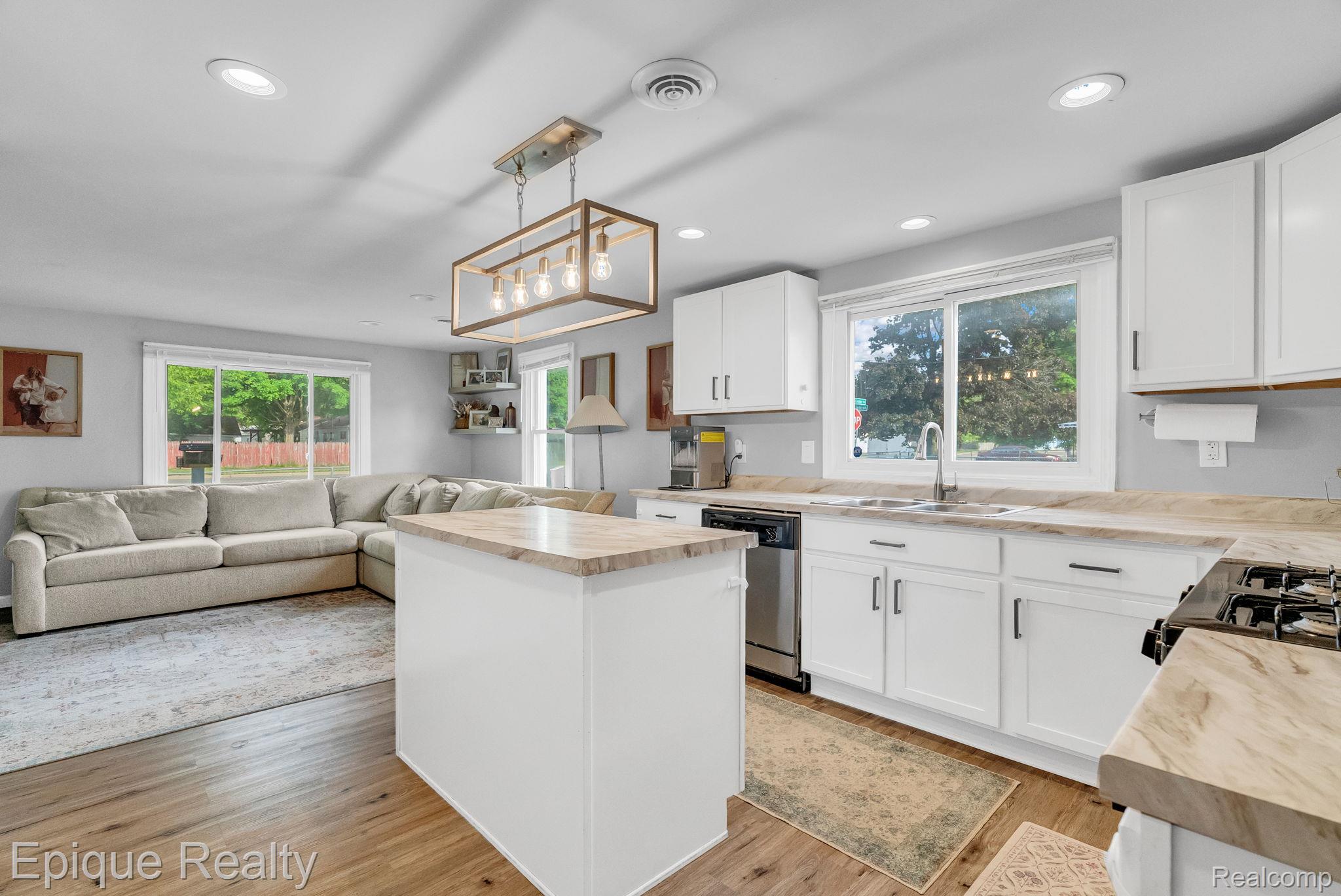2182 North Center Road Burton, MI 48509 - Photo 12 of 34 Open-concept kitchen featuring an island, white cabinetry with dark hardware, a stainless steel sink, and wood-finish flooring