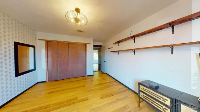 a view of an empty room with window and wooden floor