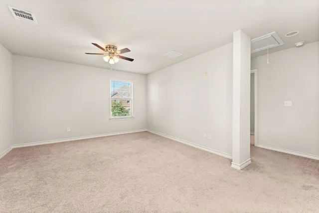 an empty room with chandelier fan and windows