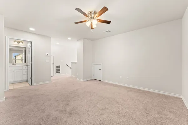 an empty room with chandelier fan and windows