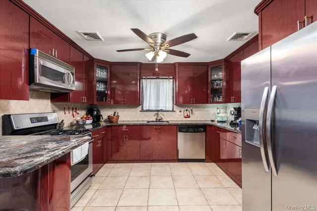 a kitchen with stainless steel appliances granite countertop a stove a sink dishwasher a refrigerator and a microwave
