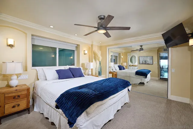 a spacious bedroom with a bed a dresser and a chandelier