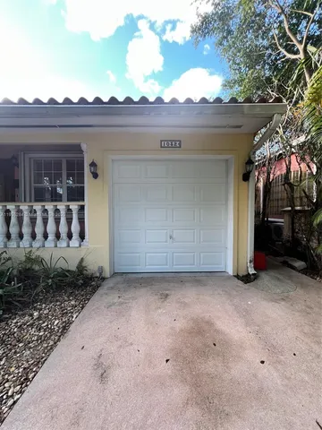 a view of a house with a small yard and a large tree