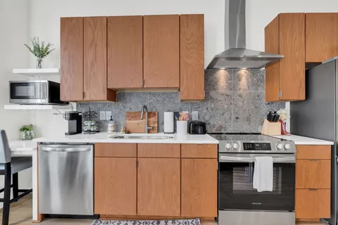 a kitchen with stainless steel appliances granite countertop a stove a sink and a white cabinets