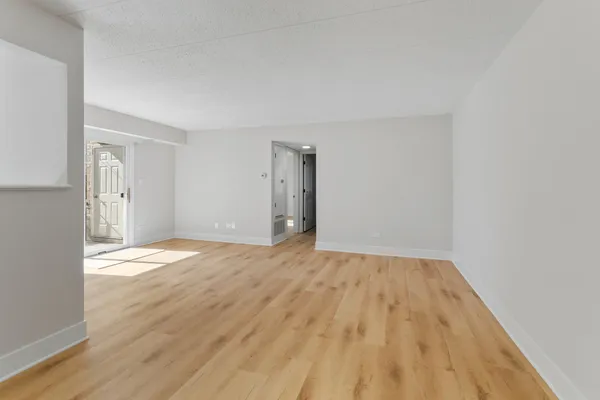 a view of an empty room with wooden floor and a window