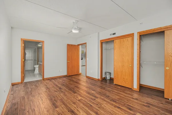 a view of an empty room with wooden floor and closet