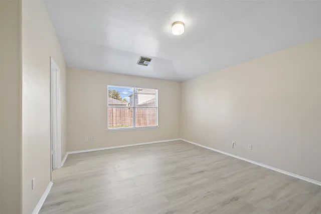 a view of an empty room with a window and wooden floor