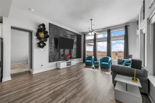 a living room with furniture large window and wooden floor