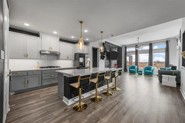 a kitchen with stainless steel appliances granite countertop a stove top oven a refrigerator a sink and white cabinets with wooden floor