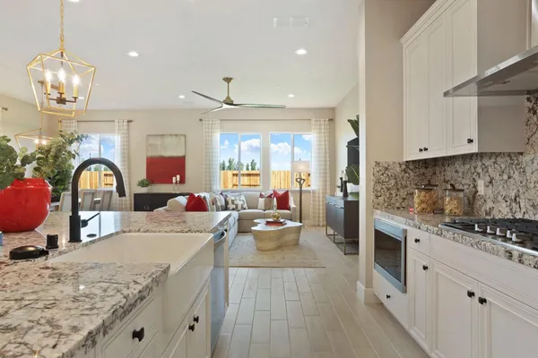 a kitchen with stainless steel appliances granite countertop a sink dishwasher stove and white cabinets with wooden floor