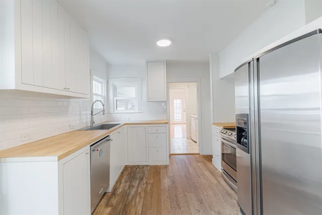 a kitchen with granite countertop white cabinets and white appliances with wooden floor