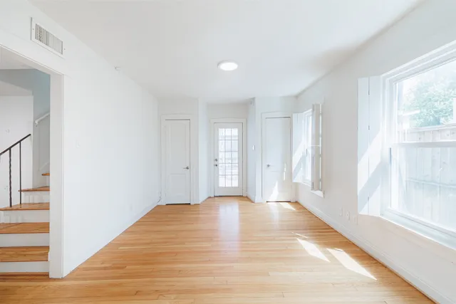 a view of an empty room with window and wooden floor