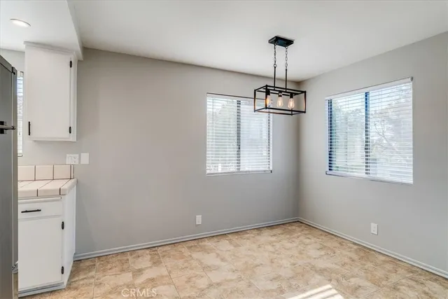 a view of an empty room with window and chandelier