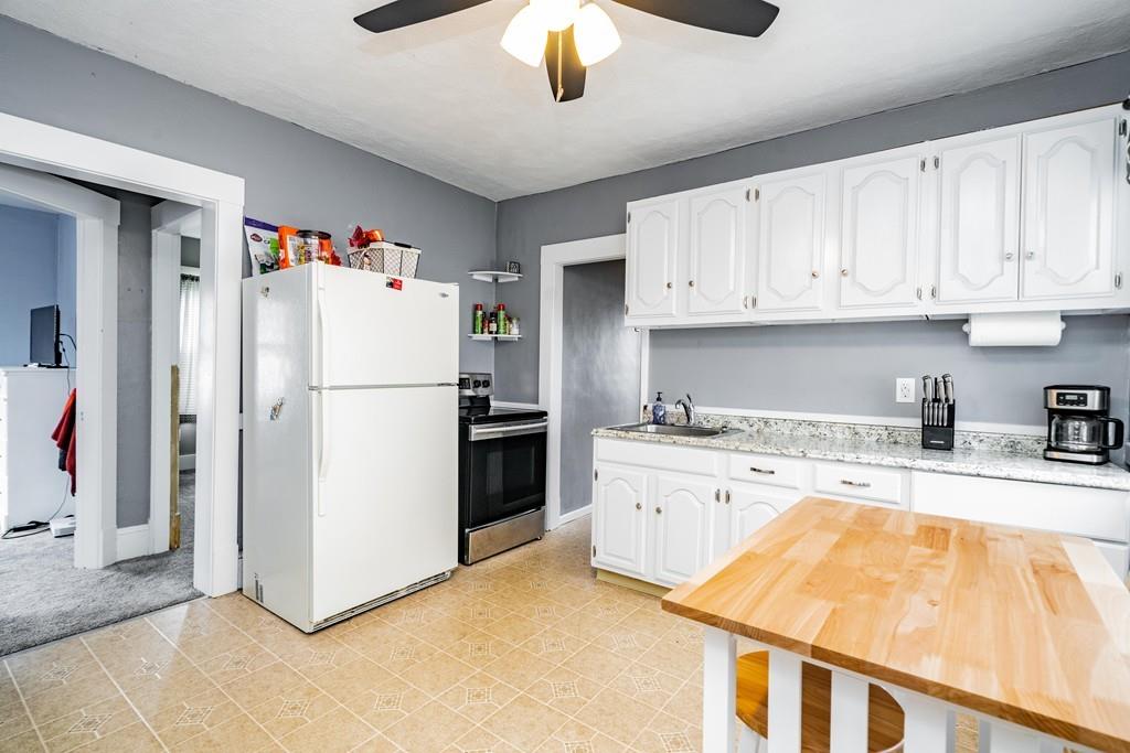 47 Richelieu Street Chicopee, MA 01020 - Photo 15 of 34 a kitchen with granite countertop a refrigerator a stove a sink and white cabinets