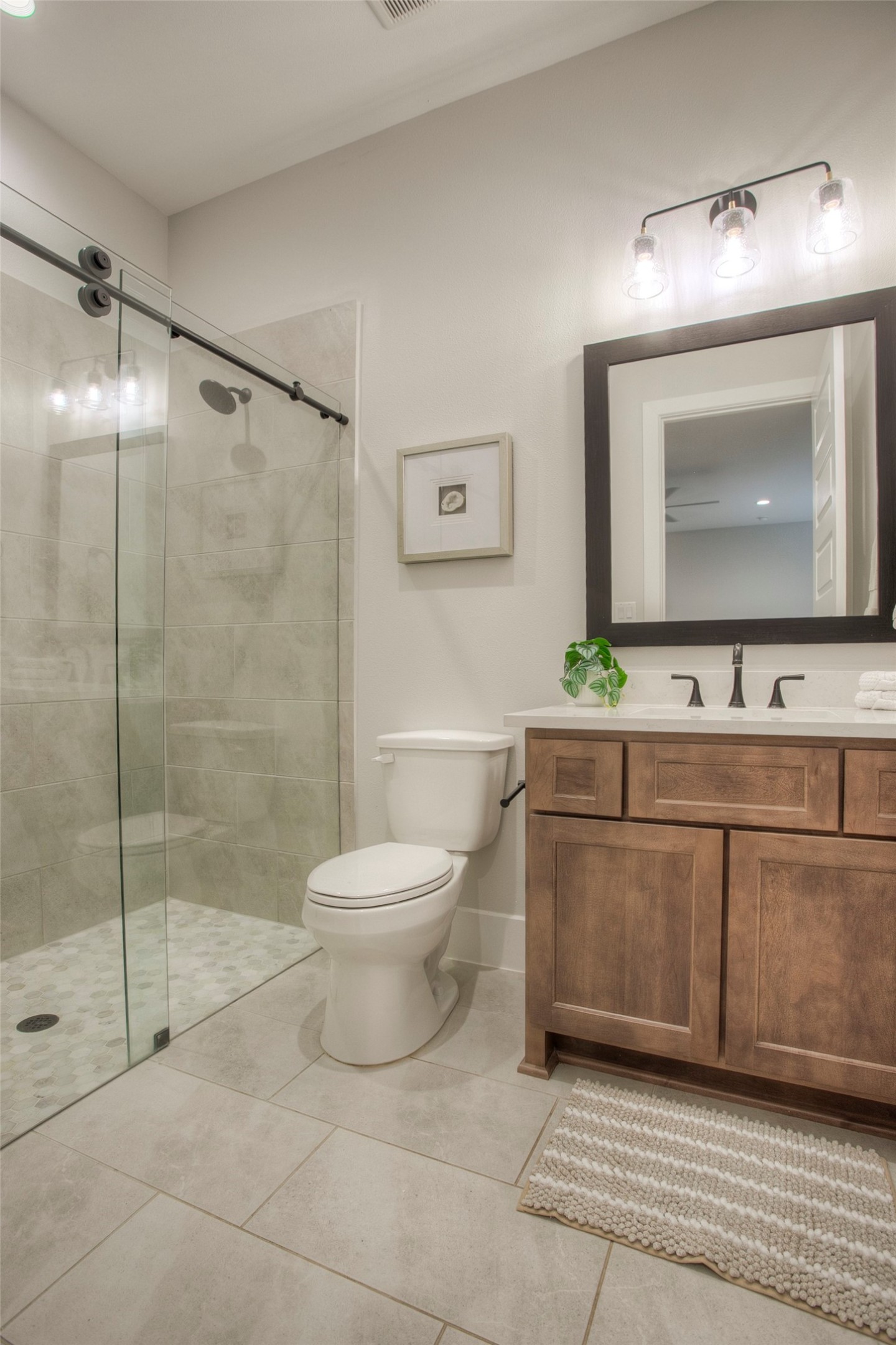 12915 Oak Barrel Road Willis, TX 77378 - Photo 30 of 46 This bathroom features a modern design with a spacious walk-in shower, glass sliding doors, and sleek tile work. It includes a wooden vanity with a large mirror and elegant lighting.