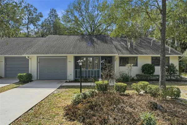 a backyard of a house with potted plants and large tree