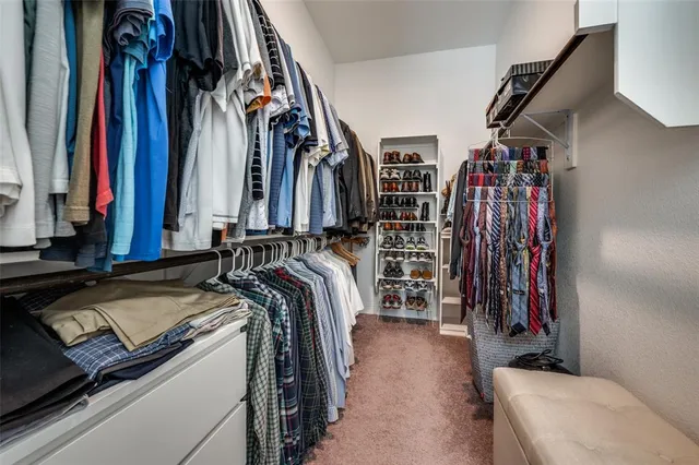 a view of walk in closet with clothes and shoes