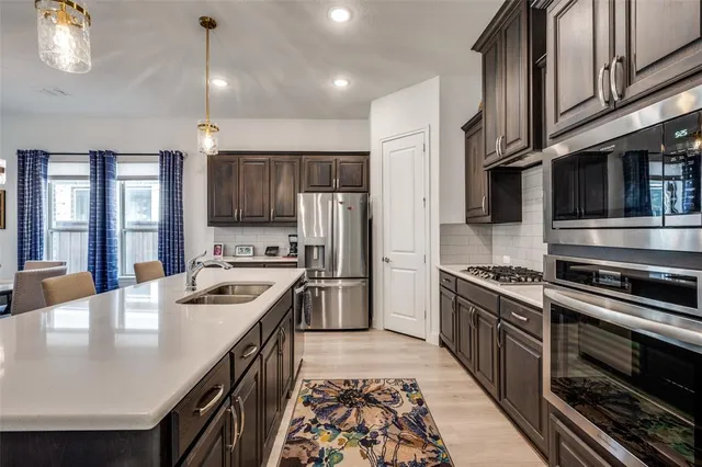 a kitchen with stainless steel appliances granite countertop a stove a sink and a refrigerator