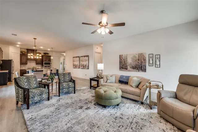 a living room with furniture kitchen view and a chandelier