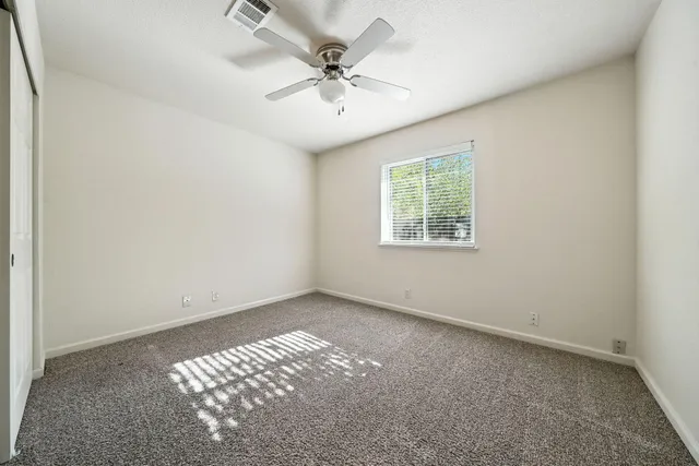 an empty room with windows and fan