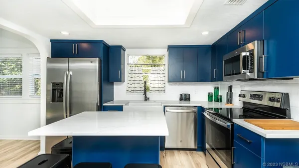 a kitchen with stainless steel appliances granite countertop a refrigerator a stove a sink a microwave and island