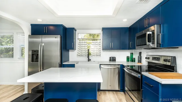 a kitchen with stainless steel appliances granite countertop a refrigerator a stove a sink a microwave and island