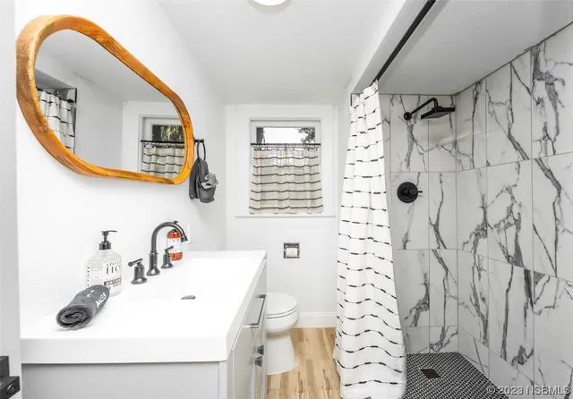 a room with wooden floors pool table and windows