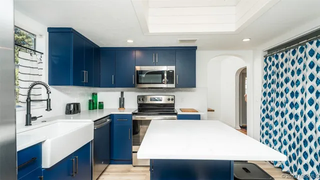 a kitchen with stainless steel appliances granite countertop a refrigerator a sink dishwasher a stove top oven a dining table and chairs with wooden floor