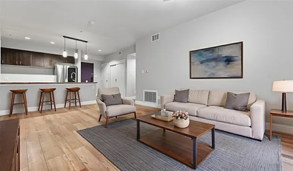 a living room with furniture a wooden floor and kitchen view
