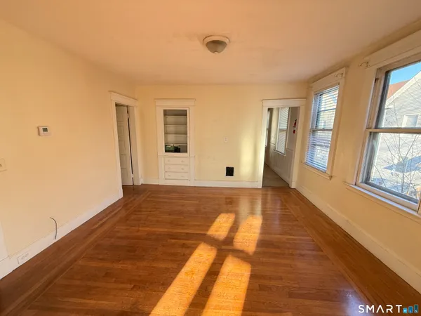 a view of an empty room with window and wooden floor