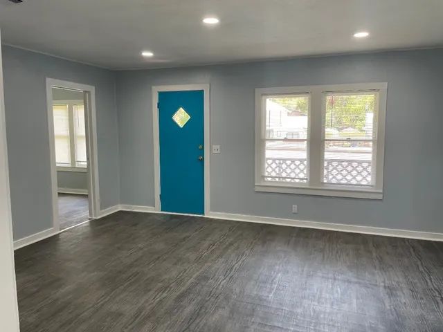 an empty room with wooden floor and windows